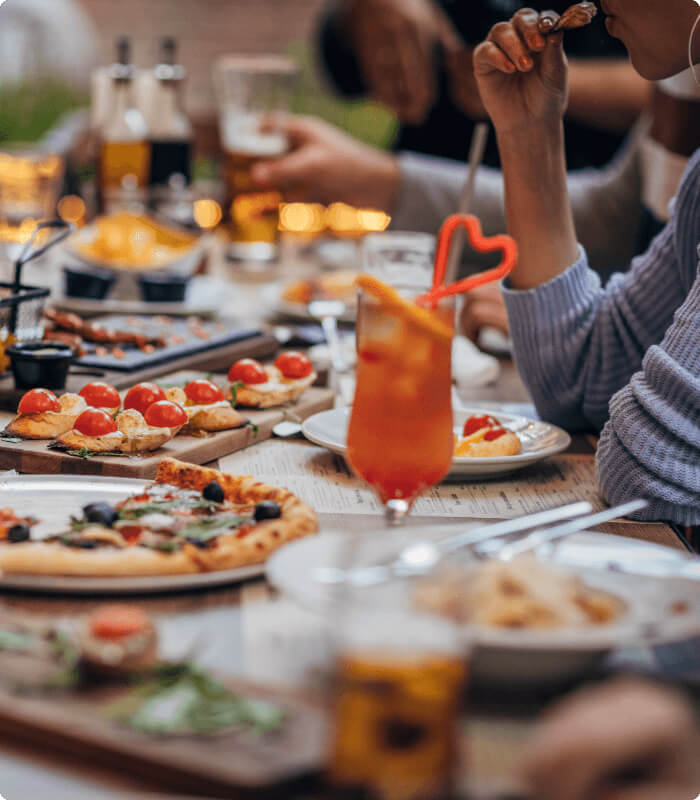 Guests enjoy pizza, appetizers, and cocktails at Village Clubs Camelback, in a lively and festive dining atmosphere.