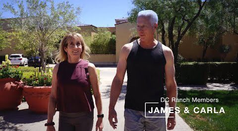 Village Clubs members enjoy a sunny walk outdoors at DC Ranch, wearing athletic gear, with trees and a building behind them.