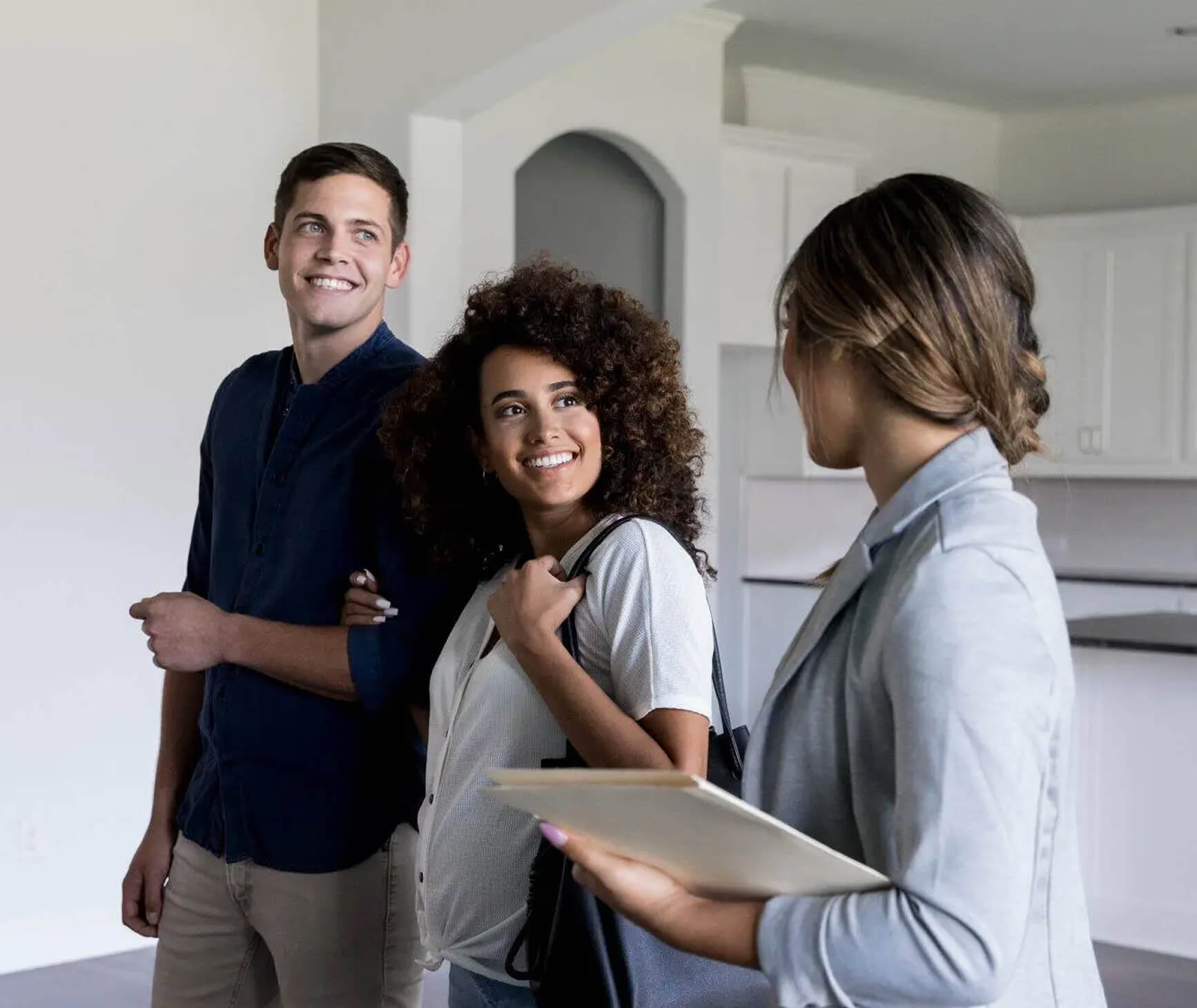 A smiling couple tours a modern kitchen in Village Clubs at Camelback with a real estate agent as part of a trusted Realtor Program.